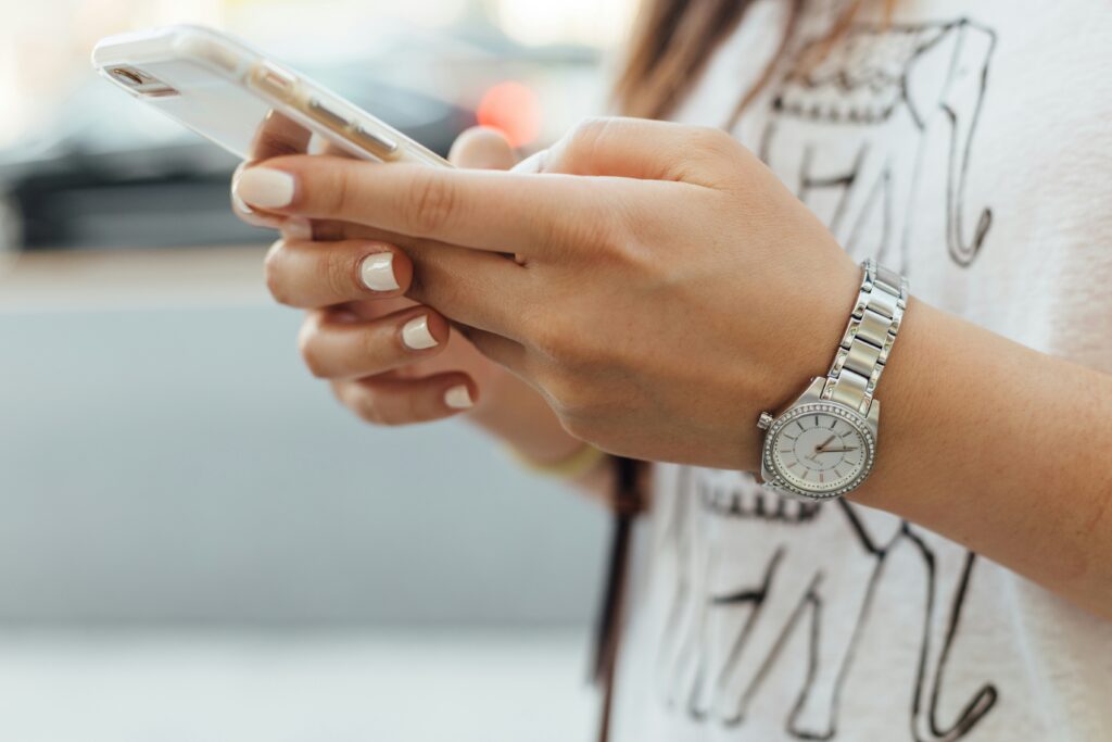 close-up image of a young woman holding a cell phone. Neutral and light colors.